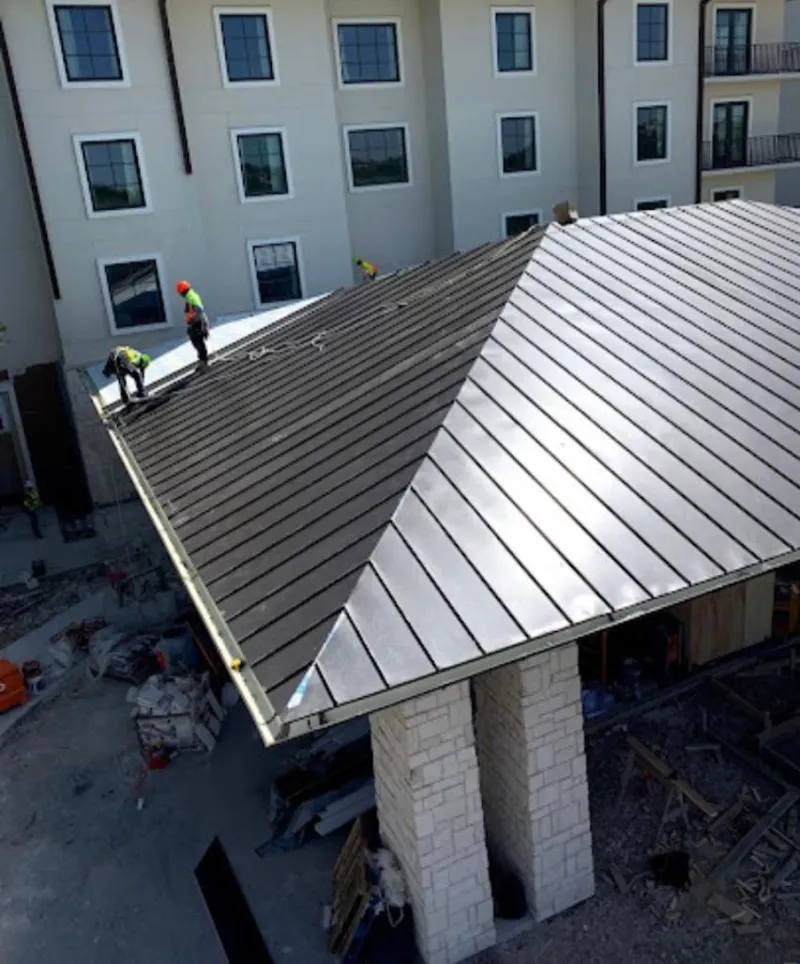 Crew installing standing seam metal roof panels on a commercial project in Yazoo City